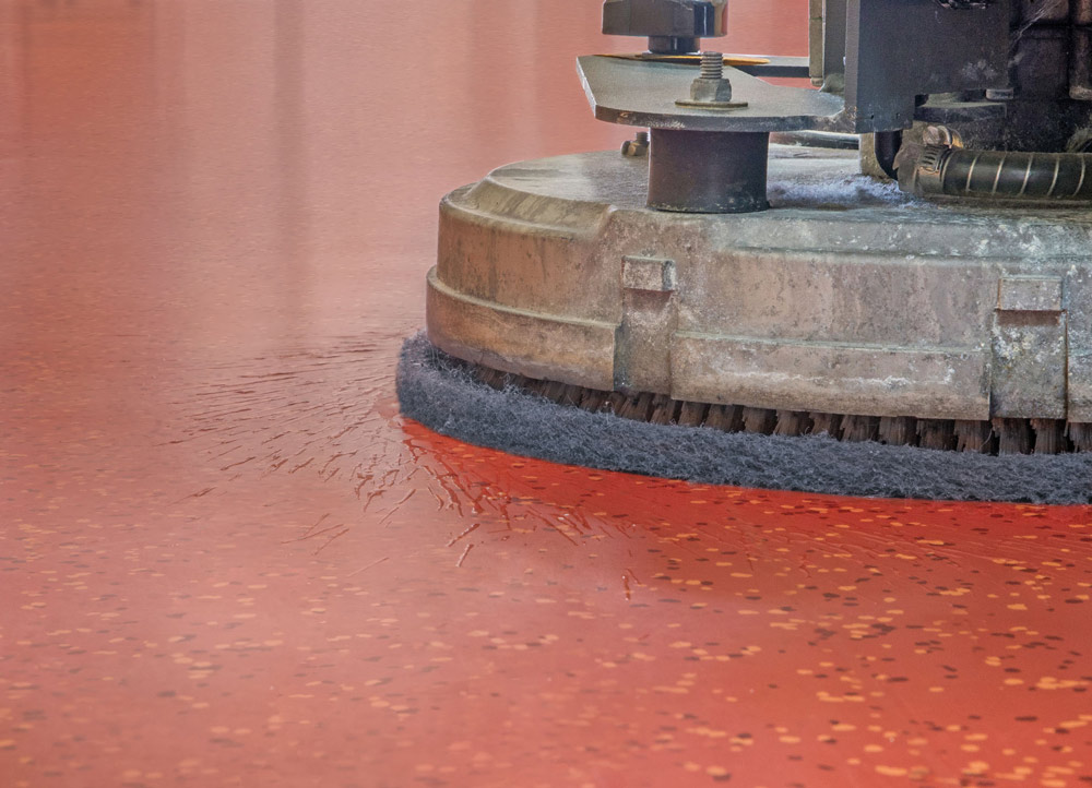 Reinigungsmaschine bestückt mit nora pad im Einsatz auf Kautschukboden in rot-orange