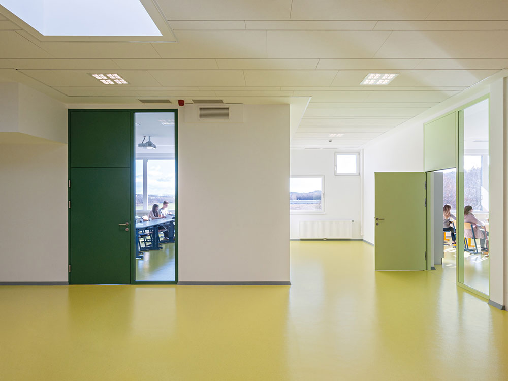 Los revestimientos de caucho nora color verde hacen un atractivo contraste con las paredes blancas de la institución educativa