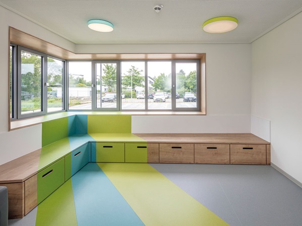 Farbige Streifen im hellgrauen Bodenbelag symbolisieren Lichtstrahlen. Der Belag wurde auch auf den Podestlandschaften und über die Wänden bis zum Fenster verlegt