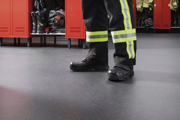 Füße eines Feuerwehrmanns in Stiefeln in Umkleide, Feuerwehrhaus. Bodenbelag: noraplan stone Kautschuk-Bodenbelag
